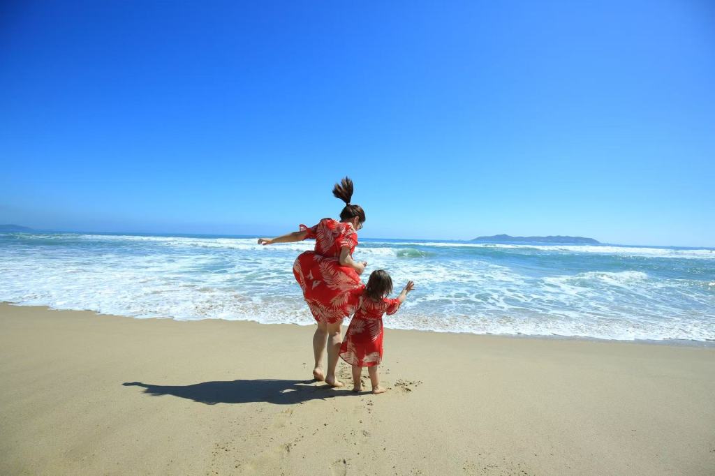 A Chinese mother and her daughter seen from behind by the sea, representing family, motherhood, and life between cultures.